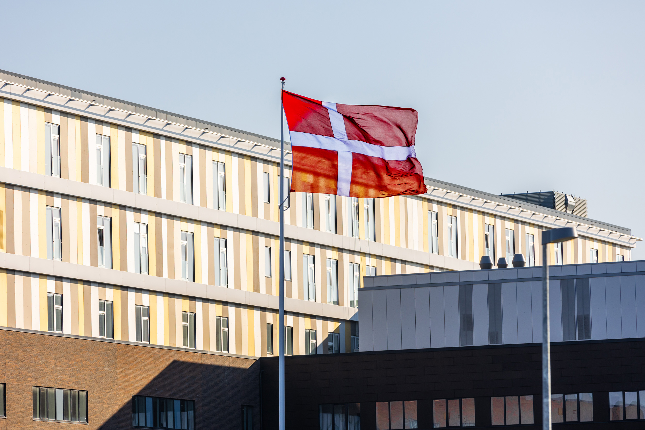 Et billede af en bygning, i forgrunden er der hejst et Dannebrog flag